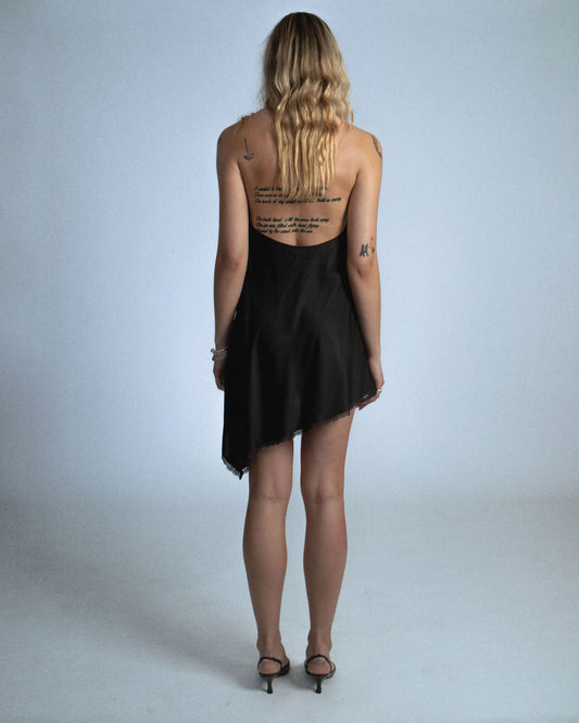 Silk cowl neck mini dress with distressed flower and silk/yarn trims hanging. Fabric is sewn on bias. Features silk buttons to conceal dress slit or cover for a more modest look. Comes with detachable silk snap belt. Deadstock trims from Japan. Perfect for elevated day-to-night looks. Shop now at Sivan Studio.