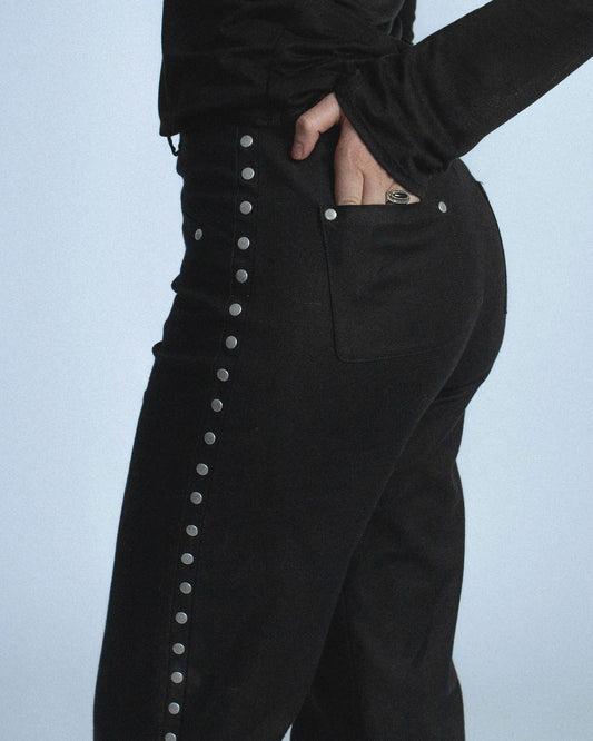 Stretch twill pants with matte silver rivets tracing the side seams. Features front welt pockets and back patch pockets. Custom laser engraved button hardware. Perfect for elevated day-to-night looks. Shop now at Sivan Studio.