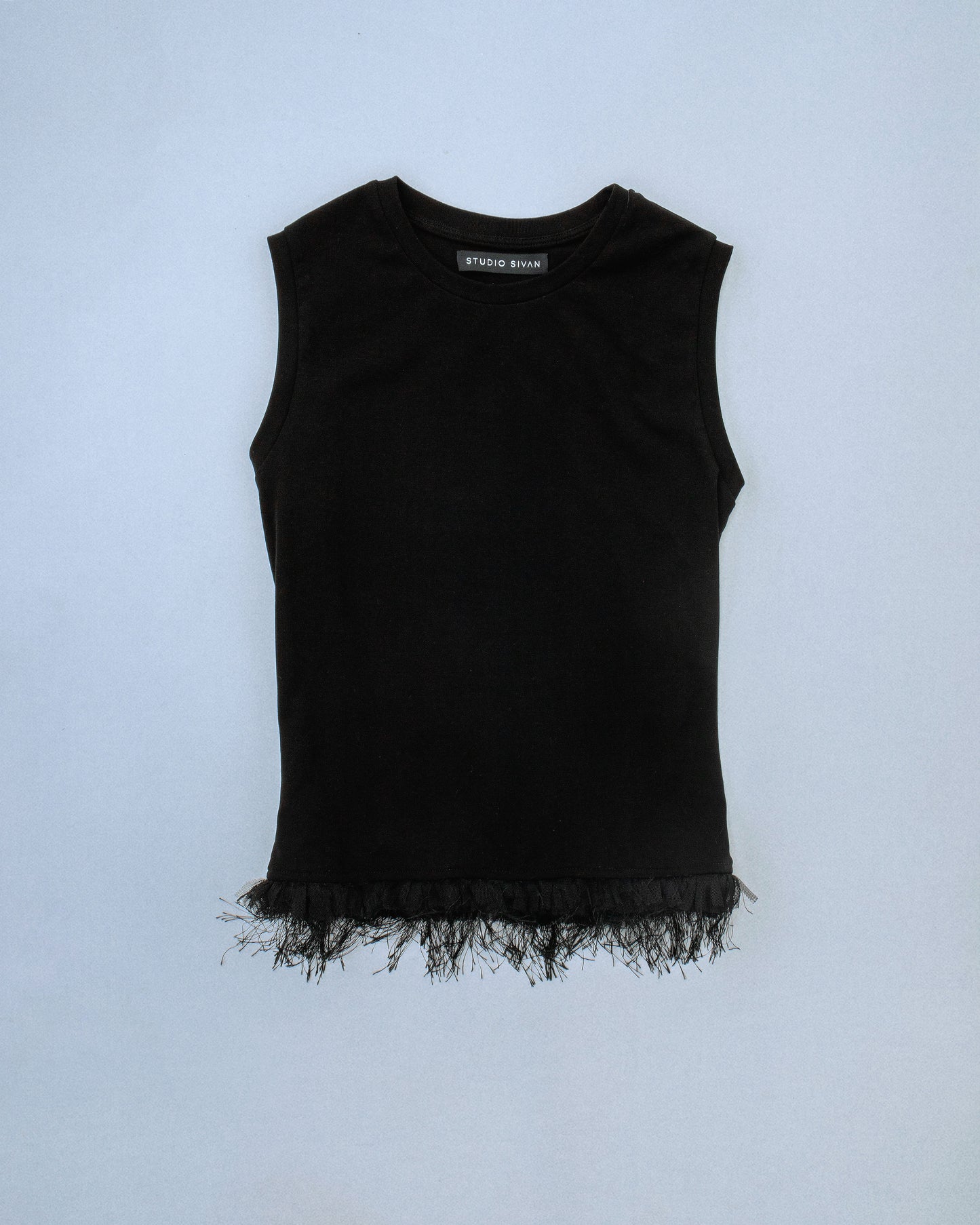 Fitted stretch cotton tank with layered trim made of lace, tulle, and distressed eyelash fringe. Softly frayed texture adds contrast to the clean silhouette. Perfect for elevated day-to-night looks. Shop now at Sivan Studio.