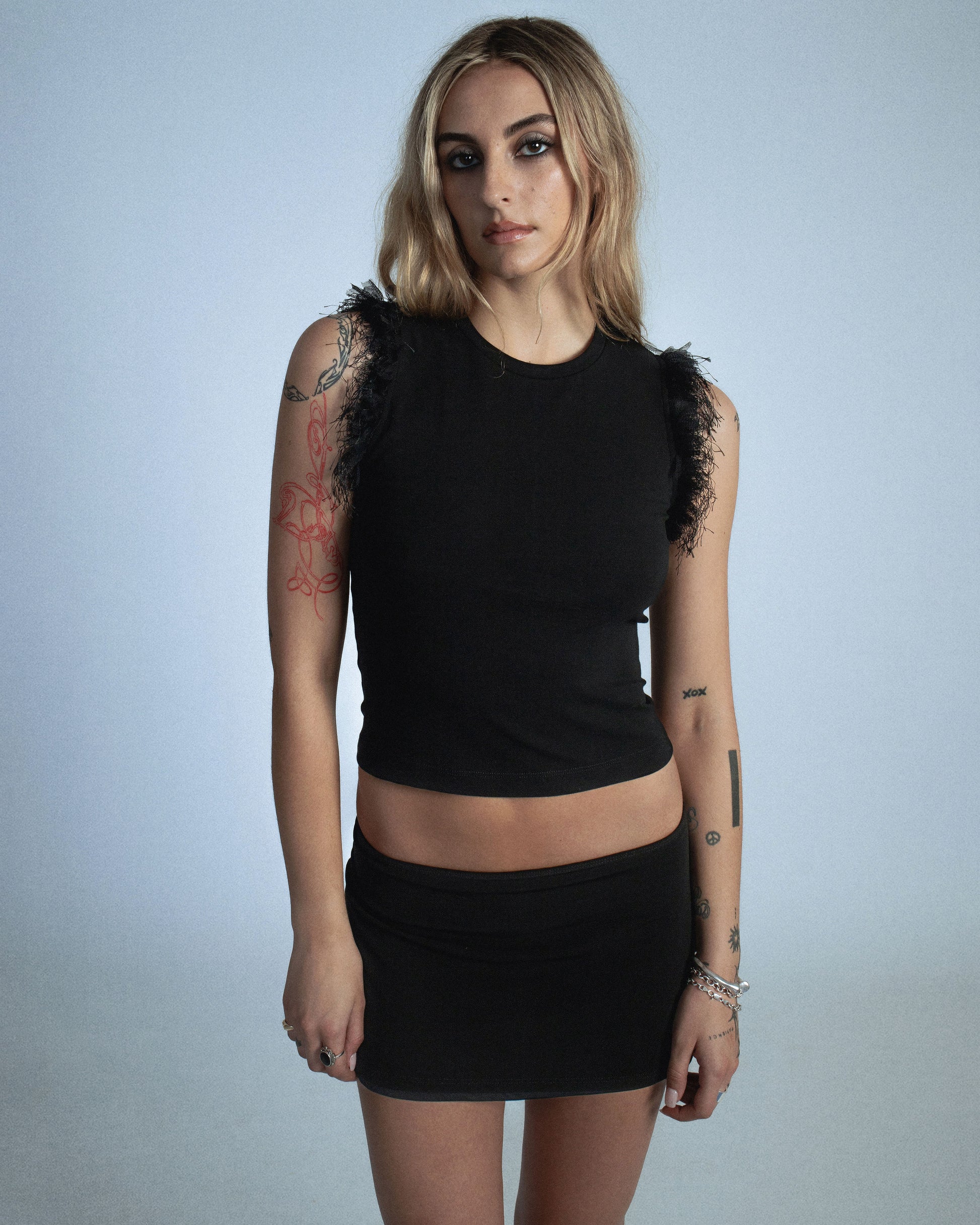 Fitted stretch cotton tank with layered trim made of lace, tulle, and distressed eyelash fringe along the sleeve opening. Adds an undone, tactile detail to a clean silhouette. Perfect for elevated day-to-night looks. Shop now at Sivan Studio.