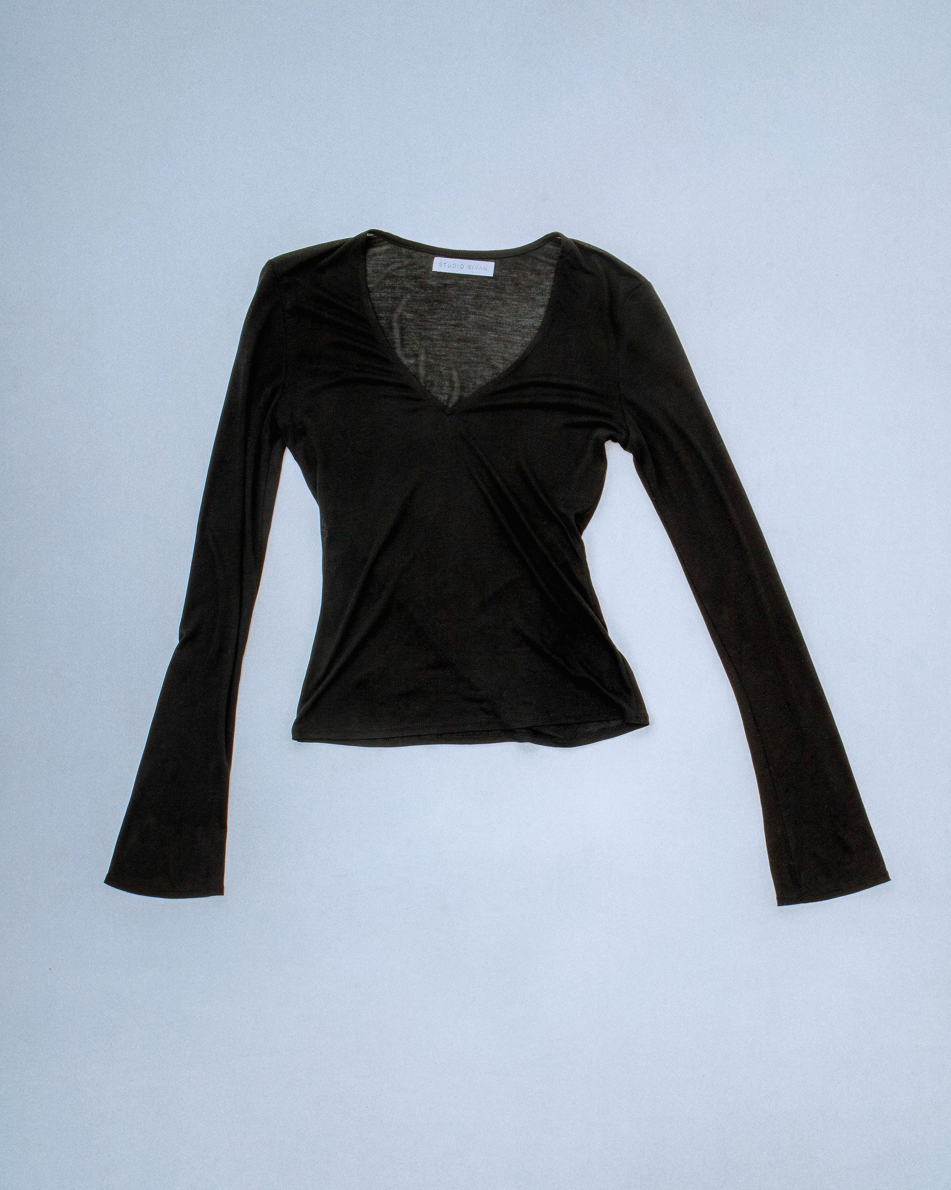 Sheer long sleeve soft knit top with a detachable overlay. Features a laser logo engraved neck clasp to secure back neck in gunmetal. Super soft, stretchy, and breathable fabric. Feels like a second skin. Perfect for elevated day-to-night looks. Shop now at Sivan Studio.