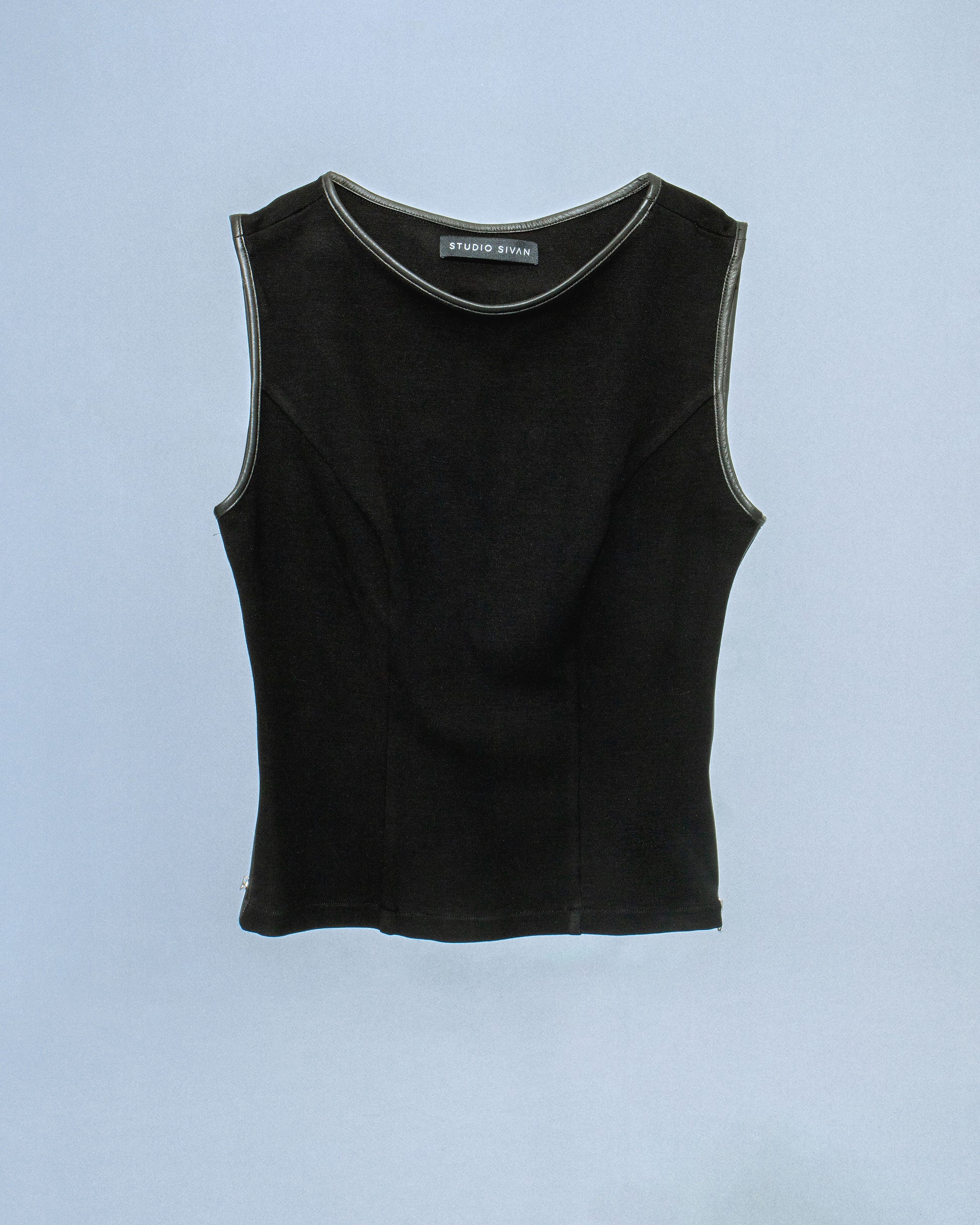 Ponte stretch tank top with lamb leather binding. Princess seams to hug figure. Features side seam zippers and back zipper. Sleeves and neckline also wrapped in leather. Perfect for elevated day-to-night looks. Shop now at Sivan Studio.