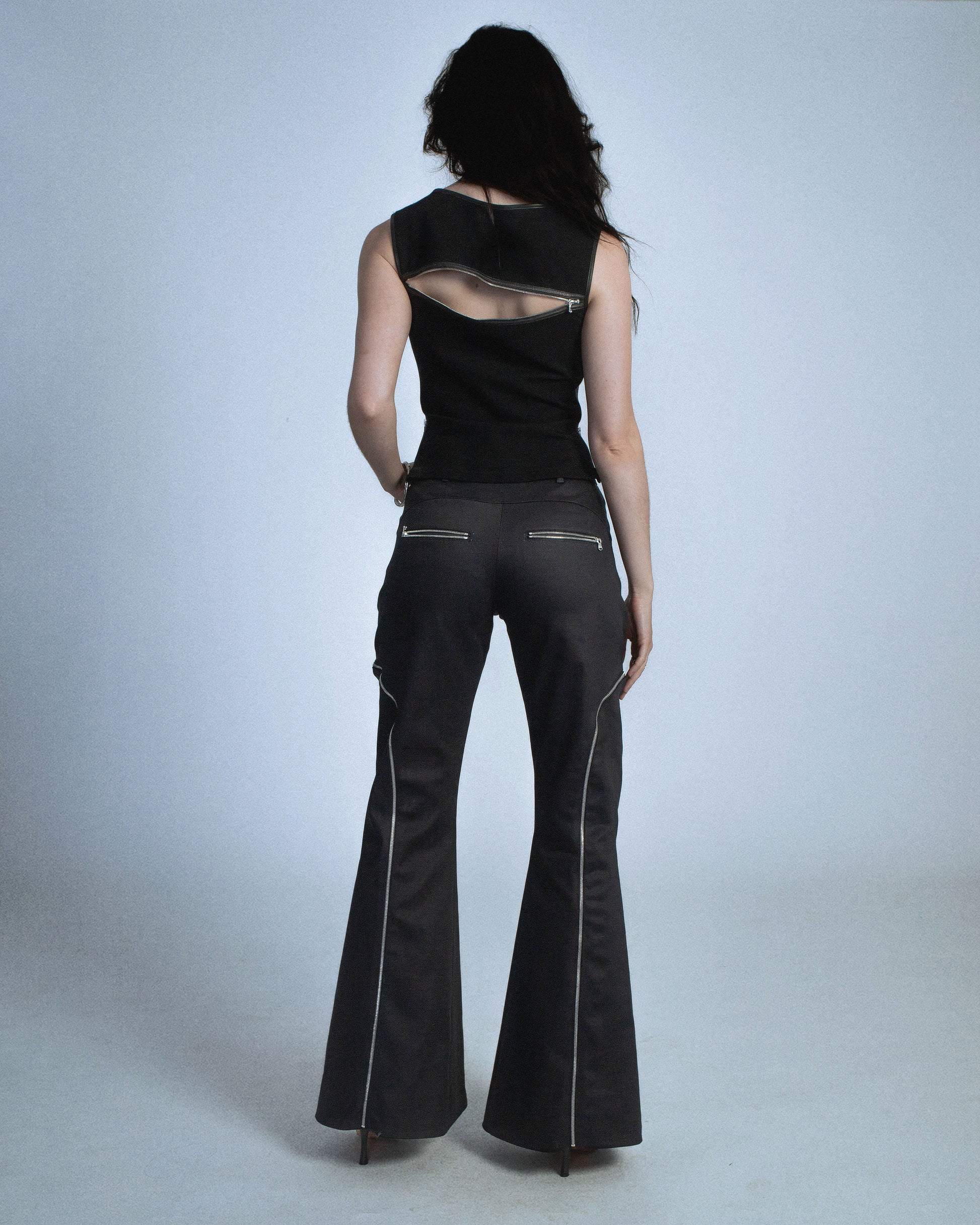 Flared waxed stretch denim zipper pant.  Zipper opens up until knee to flare pant leg even more. Features exposed front and back silver zippers. Custom laser engraved button hardware. Perfect for elevated day-to-night looks. Shop now at Sivan Studio.