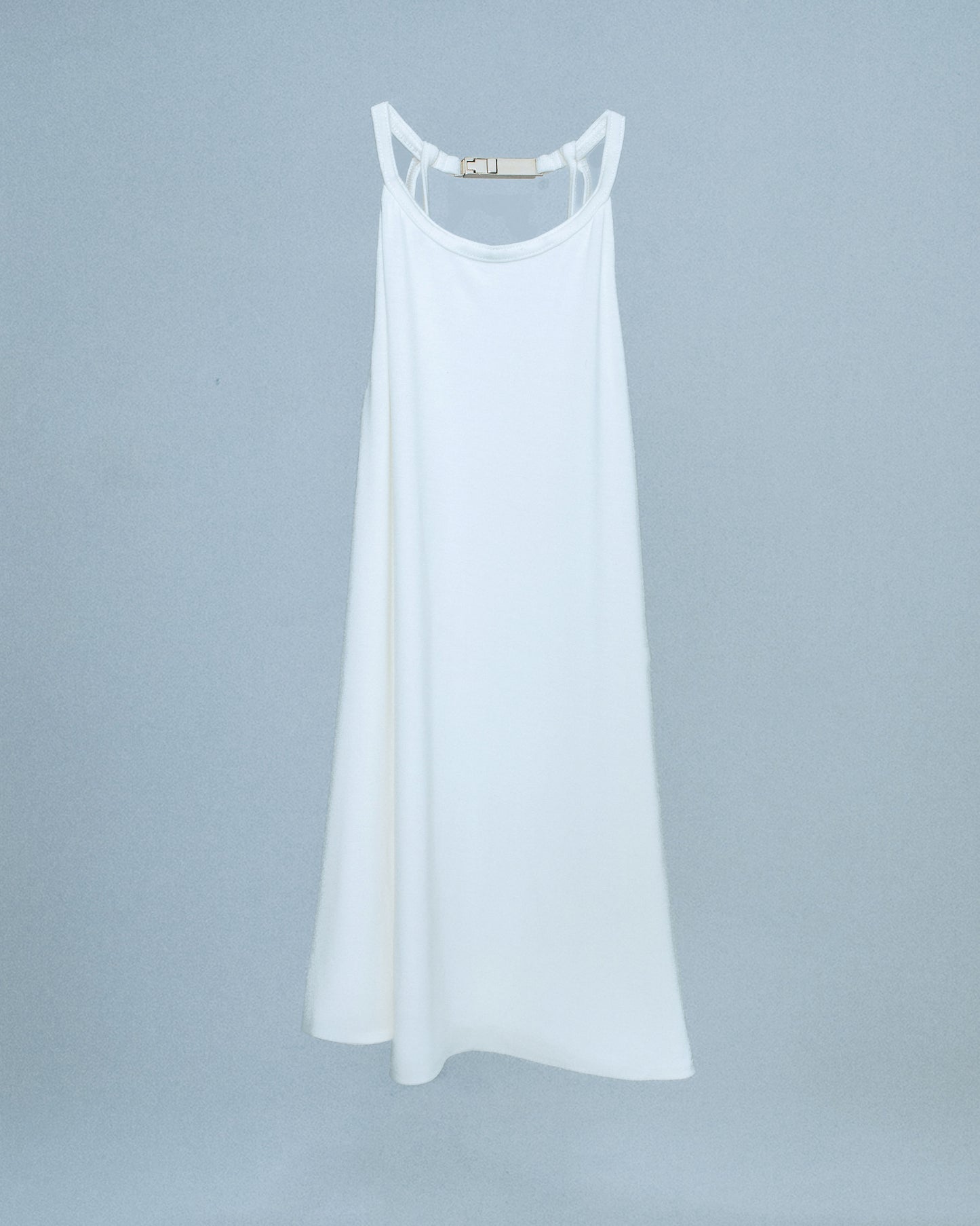 Halter neck top with a soft, fluid drape and open back. Twisted at the lower back with delicate strap detailing. Secured with an engraved silver studio Sivan logo clasp at the neck that clicks to open. Available in black and white. Black top features gunmetal clasp. Perfect for elevated day-to-night looks. Shop now at Sivan Studio.