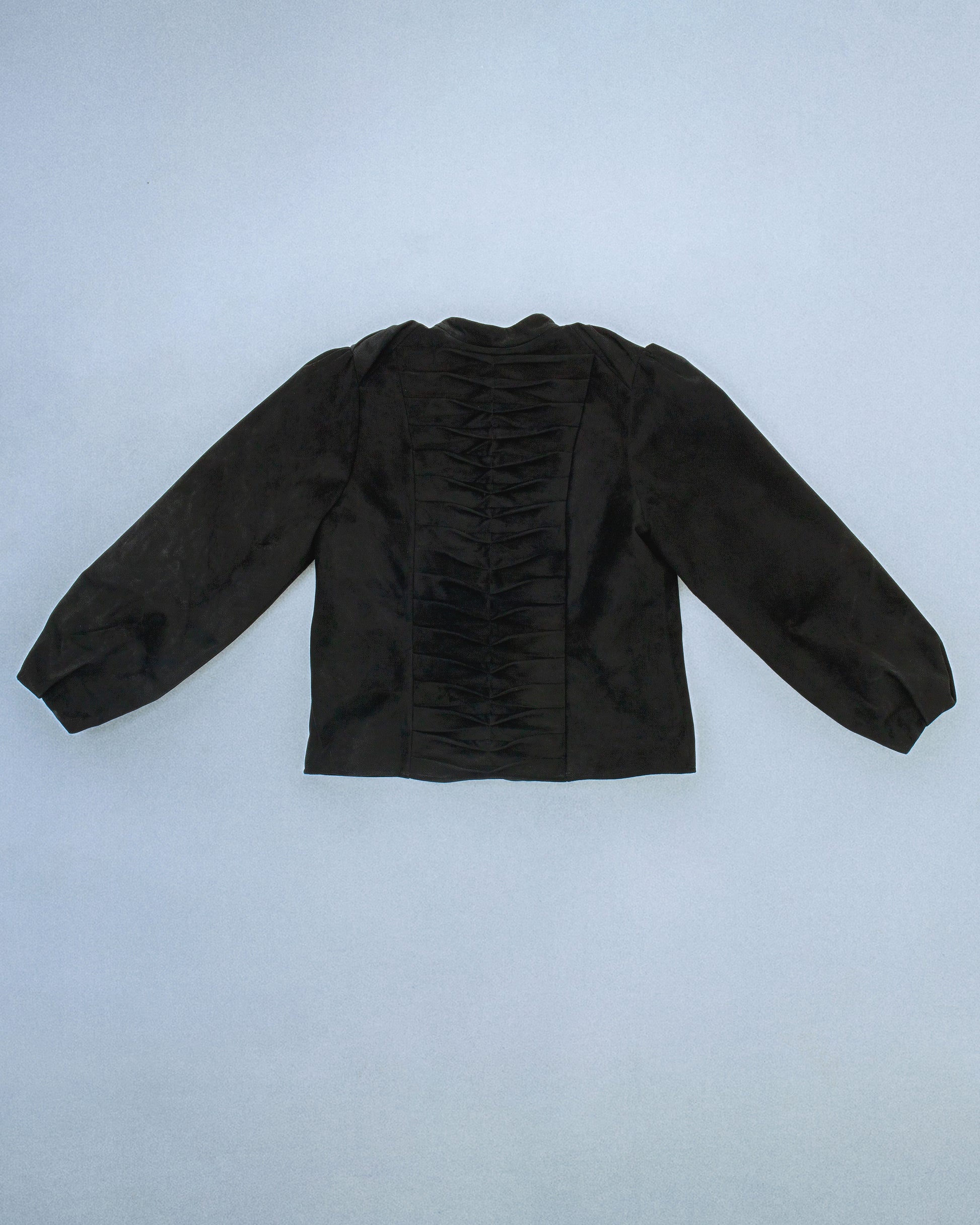 Suede jacket with exposed gunmetal zippers and soft balloon sleeves. The back features structured, sewn-down panel pleats running down the center for a sculptural spine like effect. Perfect for elevated day-to-night looks. Shop now at Sivan Studio.
