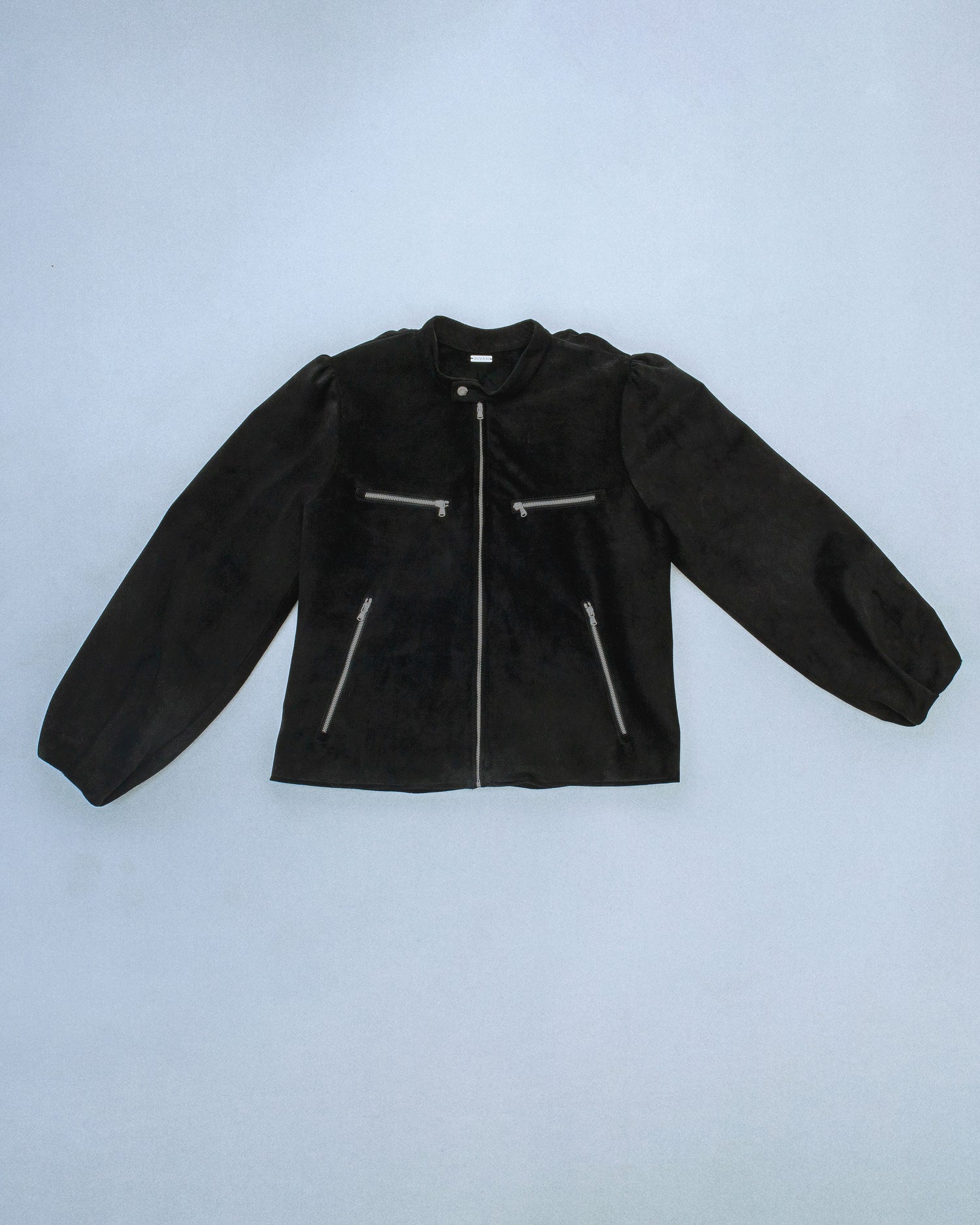 Suede jacket with exposed gunmetal zippers and soft balloon sleeves. The back features structured, sewn-down panel pleats running down the center for a sculptural spine like effect. Perfect for elevated day-to-night looks. Shop now at Sivan Studio.