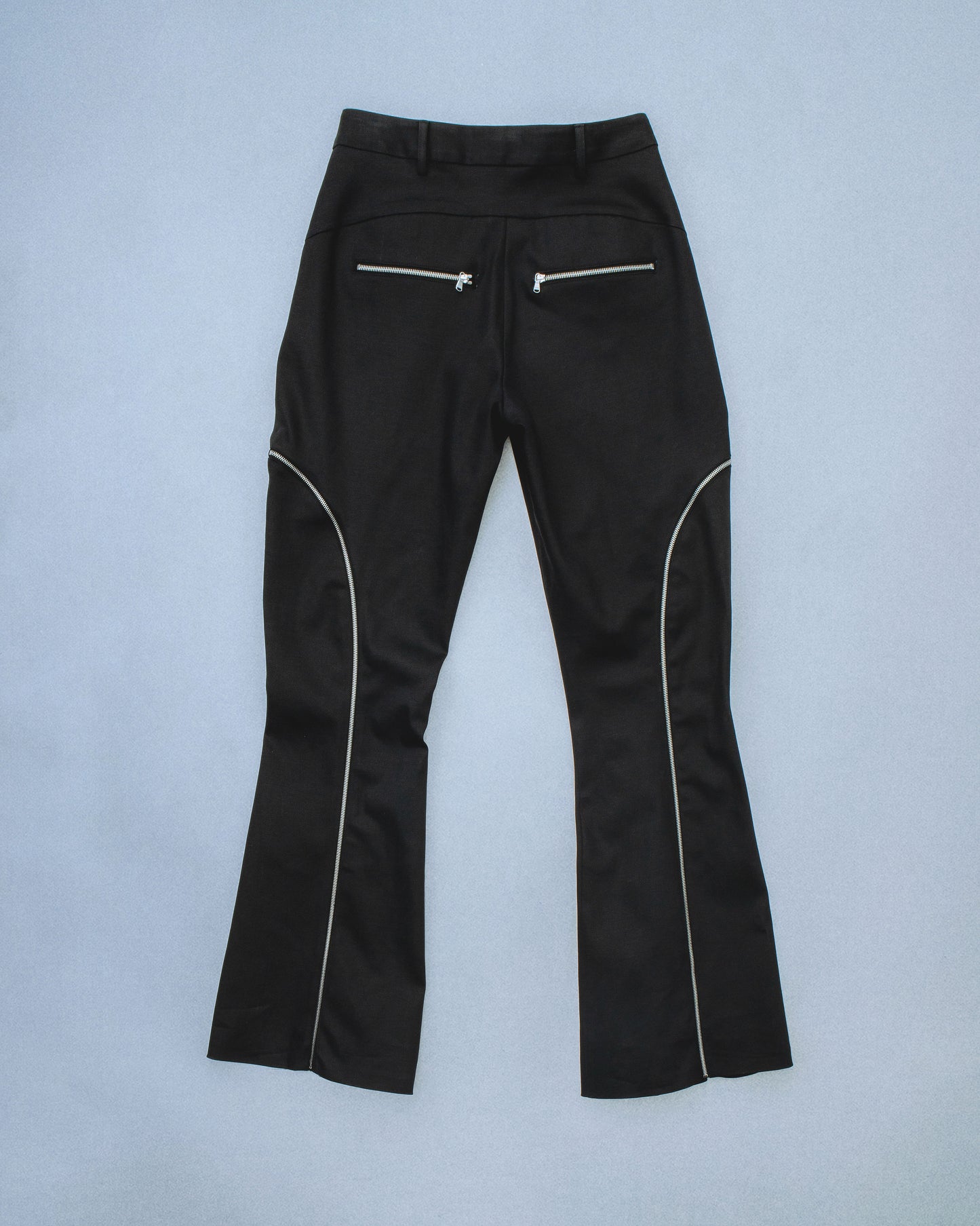 Flared waxed stretch denim zipper pant.  Zipper opens up until knee to flare pant leg even more. Features exposed front and back silver zippers. Custom laser engraved button hardware. Perfect for elevated day-to-night looks. Shop now at Sivan Studio.