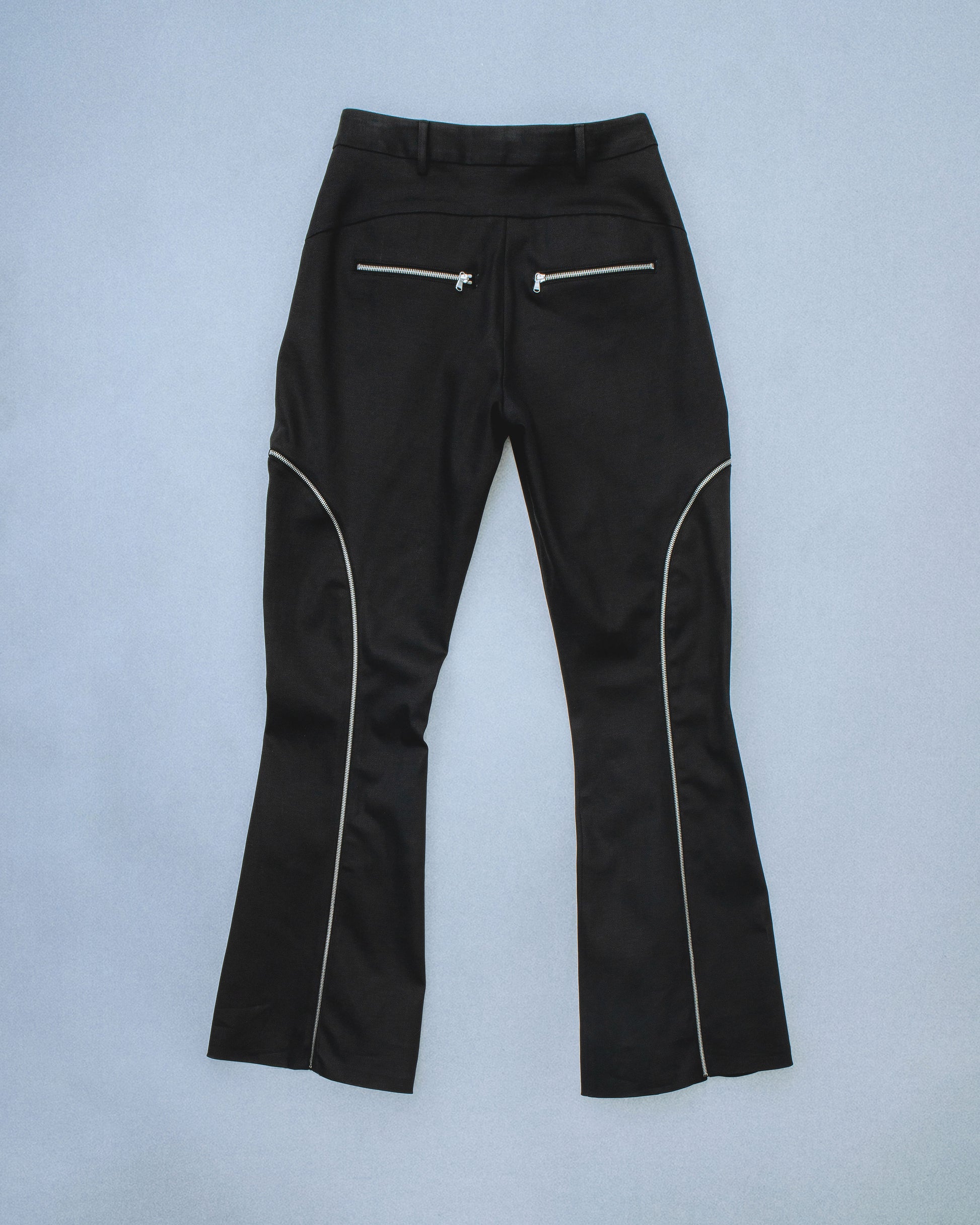 Flared waxed stretch denim zipper pant.  Zipper opens up until knee to flare pant leg even more. Features exposed front and back silver zippers. Custom laser engraved button hardware. Perfect for elevated day-to-night looks. Shop now at Sivan Studio.